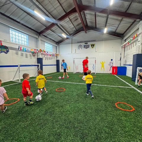 Children spread across the astro pitch working through a session with marker rings and balls
