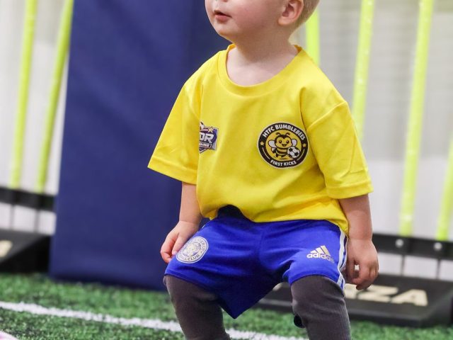 A toddler in a yellow HTFC Bumblebees shirt standing between the FORZA mannequins