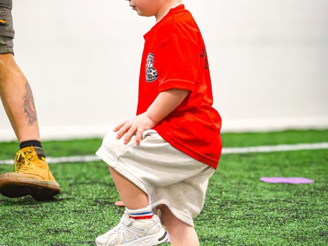 A young player in a red top with a foot up on a pink football