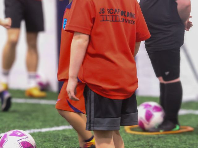 Three boys lined up at their own footballs in yellow marker rings, waiting on the coach