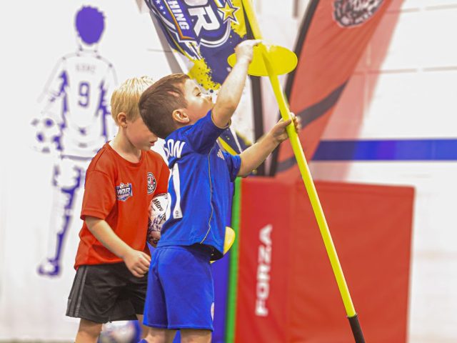 Two boys setting up a slalom pole in front of the WDR Coaching feather flag