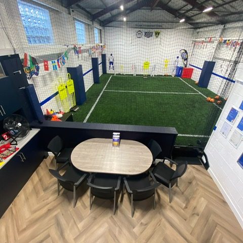 The waiting area looking down the length of the arena, with the flags of the world strung above the pitch