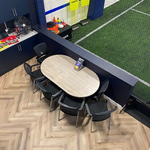 The table and chairs in the waiting area, beside the astro pitch and the training equipment